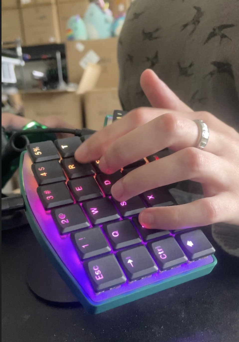 A hand typing on the left half of a Keebio Iris LM, angled on a tenting stand